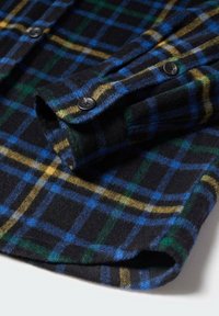 Flanellen overhemd met een zwarte basis en een blauw, groen en geel ruitpatroon. Zachte textuur en knoopsluiting bij de mouwen.