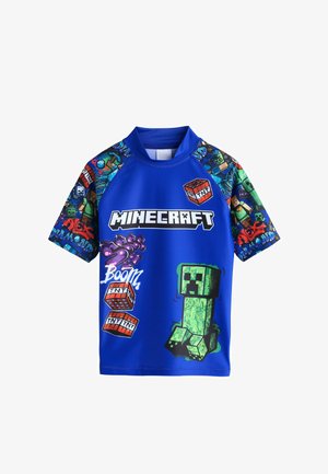 Sinine Minecrafti-teemaline lühikeste varrukatega särk, millel on TNT plokid, Creeperi graafika ja varrukatel värvikad pikslist kujundatud tegelased.