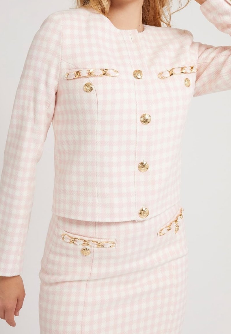 Roze blazer met ruitjespatroon, gouden knopen en kettingaccenten op de zakken. Gevoerd met textuurrijk materiaal, cropped model, klassieke ronde halslijn.