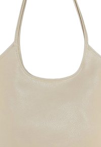 Beige handtas met een gestructureerd oppervlak, ronde opening en dunne schouderbanden voor gemakkelijk dragen. Minimalistisch ontwerp zonder zichtbare hardware.