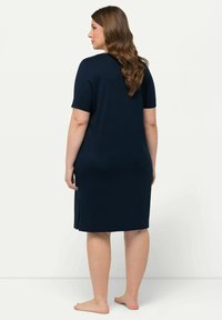 Abito blu navy a maniche corte realizzato in tessuto morbido, con spacchi laterali per facilitare i movimenti e un design semplice e classico.
