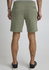 Shorts en mélange de coton vert avec un design simple, une taille élastique et une poche arrière. Présentent des ourlets cousus et une texture douce.
