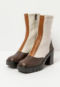 Botas de tobillo marrones y crema con un alto tacón en bloque, cierre de cremallera, cuero texturizado y paneles de colores contrastantes. Incluye detalles de costura.