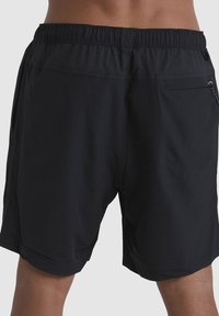 Shorts actifs noirs avec une taille élastique, des poches latérales et une poche arrière. Fabriqués en tissu léger avec une texture lisse.