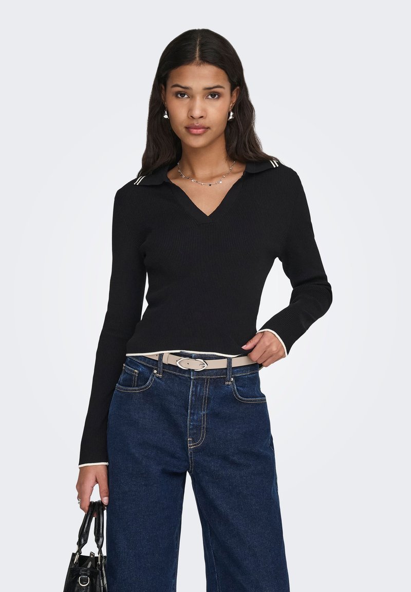 Pull noir côtelé avec col en V et détails de col rayé, associé à un jean bleu taille haute et une ceinture claire. Accessoires : un petit sac noir.