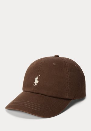 Gorra de béisbol marrón con visera curva y un pequeño logotipo blanco de un jugador de polo, sobre un fondo liso y claro.