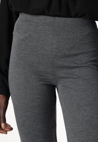 Gray textured leggings with a high waist and fitted design, made of a soft, stretchy material, feature subtle patterns and seam detailing.