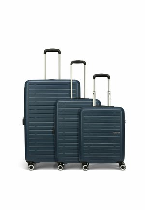 Tre valigie rigide di colore blu navy con scanalature orizzontali, manici telescopici argentati e quattro ruote ciascuna per una facile manovrabilità.