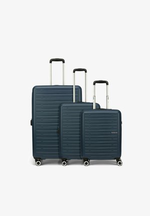 Tre valigie rigide di colore blu navy con scanalature orizzontali, manici telescopici argentati e quattro ruote ciascuna per una facile manovrabilità.