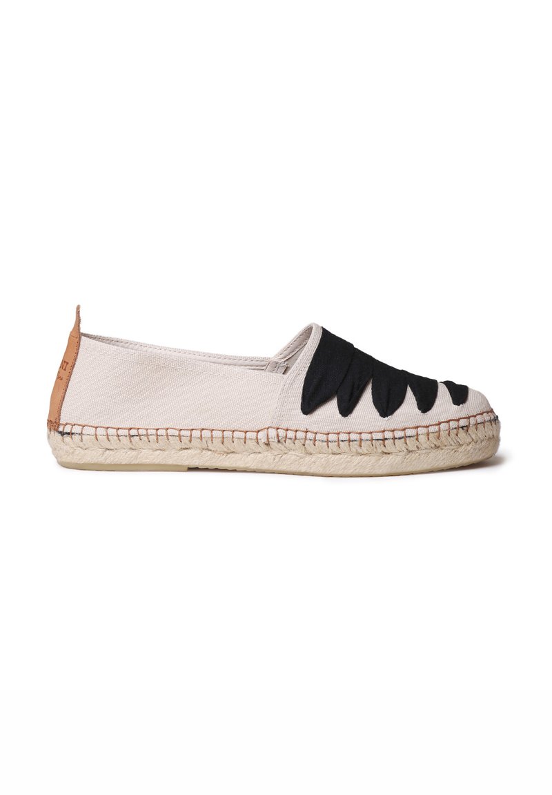 Espadrille en toile beige avec des accents décoratifs noirs. Semelle plate avec garniture en jute, orteil structuré et languette de talon en cuir marron.