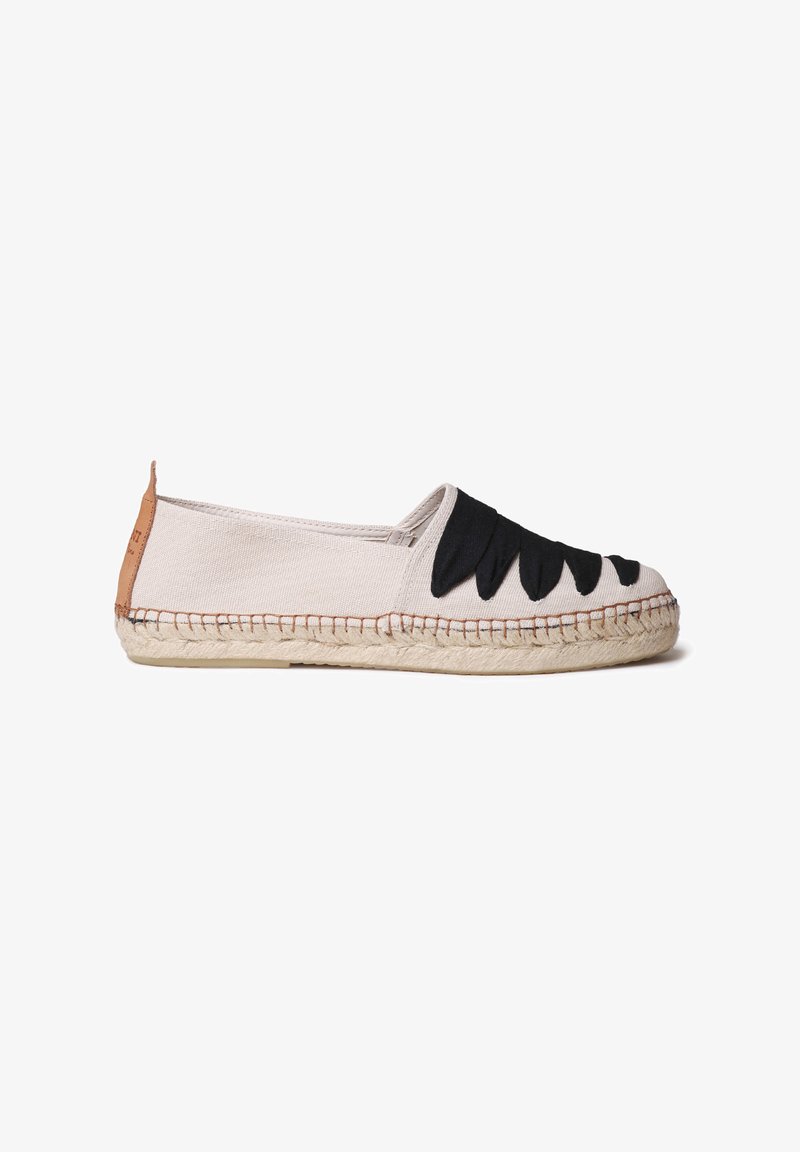 Canvas espadrille in beige with black decorative accents. Flat sole with jute trim, structured toe, and tan leather heel tab.
