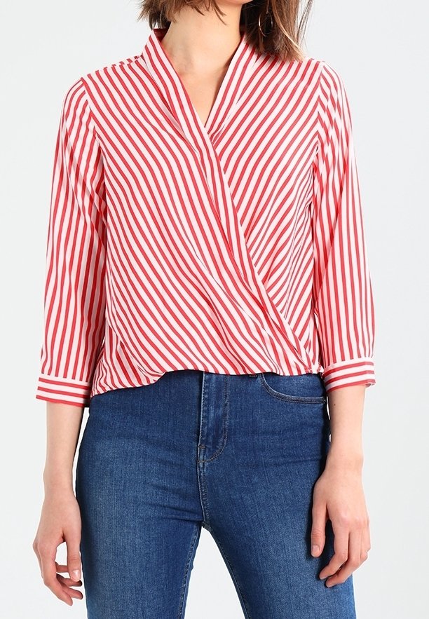 Rød og hvid stribet wrap-bluse med 3/4 ærmer, letvægtsstof, v-hals og løst fit. Båret med blå jeans.
