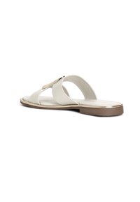 White leather sandal with an open toe design, curved straps, gold hardware accent, and a flat brown sole. Smooth texture.