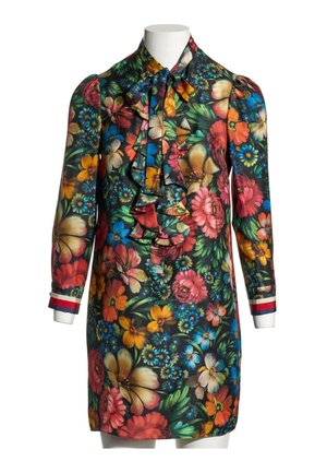 Langærmet blomsterkjole med farverige blomster, rynket front, sløjfe-krave og stribede manchetter på en hvid mannequin.