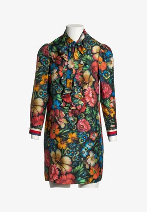 Robe à manches longues à fleurs colorées, devant volanté, col lavallière et poignets rayés sur un mannequin blanc.