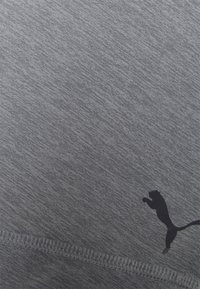 Šedá sportovní látka s jemnou melírovanou texturou, obsahující černou siluetu skákajícího lva poblíž dolního lemu.