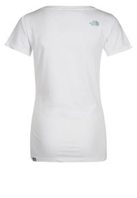 Vit bomullströja med korta ärmar, med en liten blå logotyp på baksidan nära halsringningen. Rak skärning, mjuk textur.