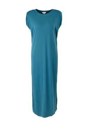 Femme portant une robe maxi sans manches bleu sarcelle avec des fentes latérales et des baskets blanches, debout devant un fond neutre.