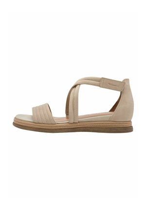 Bež sandala s ravnim potplatom, teksturiranim trakama i ukriženim dizajnom. Materijal izgleda gladak s blagim sjajem.