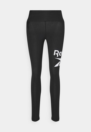 Melnas sporta leggingas no elastīgas auduma, ar augstu jostasvietu un baltu "Reebok" logo kreisajā pusē.