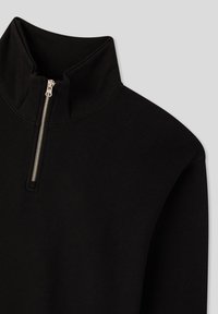 Pullover nero con zip al collo realizzato in un tessuto morbido e elasticizzato. Presenta un collo alto e dettagli in zip argentata. Texture liscia con cuciture minime.