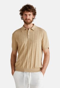 Beige short-sleeve polo shirt made from textured fabric, featuring vertical stripes, a collar, and three buttons at the neckline.