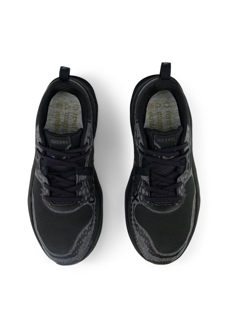 Des chaussures de sport noires avec une tige en mesh, des détails texturés et des lacets foncés. Elles présentent un logo sur la languette et une semelle rembourrée.