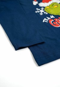 Camicia a maniche lunghe in cotone blu navy con una grafica del Grinch in cappello di Babbo Natale e il testo "TEAM GRINCH" accompagnato da design di fiocchi di neve.