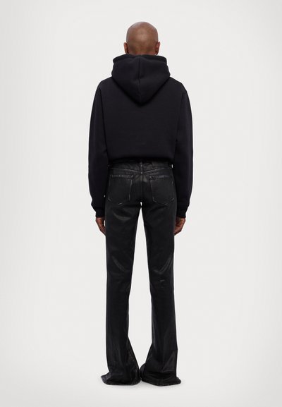 Black cropped hoodie with a large hood, paired with black high-waisted, slightly flared jeans, showcasing a glossy texture and two back pockets.