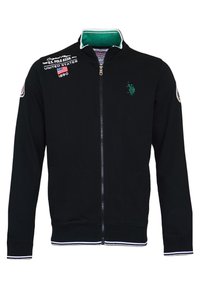 Schwarze Baumwolljacke mit Reißverschluss, ausgestattet mit einem grünen Kragen, weißen Streifen an den Bündchen und dem Saum sowie einem gestickten Logo auf der Brust.