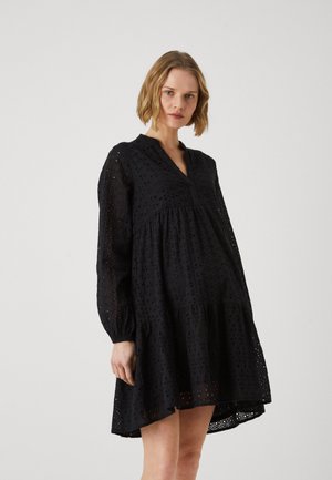 Robe en coton noir avec un design à niveaux, des manches longues et un décolleté en V. Une broderie en forme de cils ajoute de la texture, le tout avec une coupe décontractée.