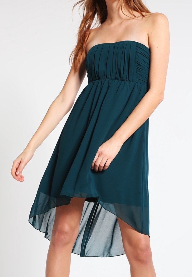Robe bustier bleu sarcelle foncé à taille haute-basse avec corsage plissé portée par une femme, jupe fluide plus courte devant et plus longue derrière.