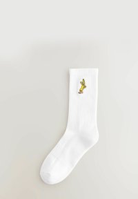 Hvide bomuldsstrømper med ribbet tekstur og en broderet design af en gul banan. Enkle og tætsiddende med en sømløs tålukning.