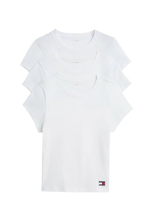 Drie effen witte T-shirts met korte mouwen gestapeld met een kleine rechthoekige rood-wit-blauwe logopatch bij de onderzoom.