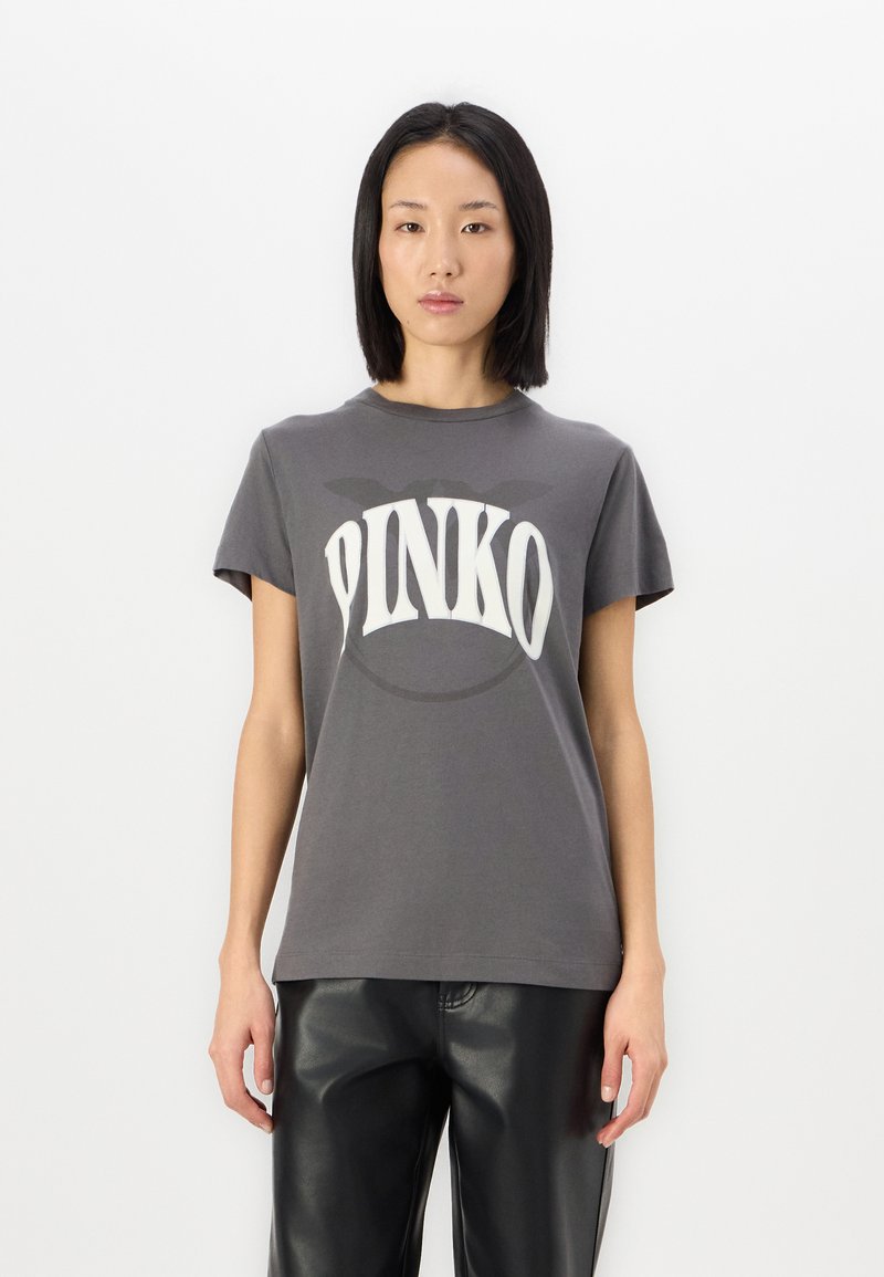 Camiseta de algodón gris con cuello redondo y mangas cortas, que presenta un texto impreso en blanco y en negrita "PINKO" en la parte delantera.
