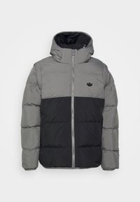 Grå och svart vadderad jacka med huva, som har dragkedjestängning och en liten svart logotyp på bröstet. Slät textur och quiltad design.