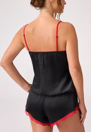 Czarny satynowy zestaw składający się z koszulki na ramiączkach i szortów z czerwonym koronkowym wykończeniem na szortach i ramiączkach. Gładka tekstura, luźny krój oraz regulowane ramiączka.
