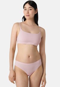 Bralette senza cuciture di un delicato rosa chiaro con spalline sottili abbinato a slip in stile bikini. Tessuto morbido e elastico con una consistenza liscia.