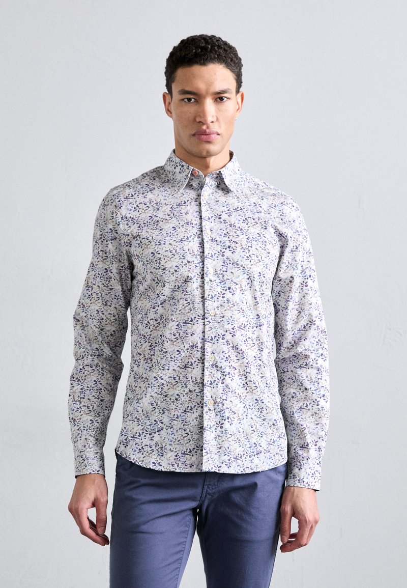 Long-sleeve button-up shirt in light fabric, featuring a floral pattern in purple and green. Soft texture with a classic collar and buttoned cuffs.