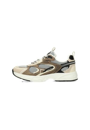 Zapatilla deportiva de rejilla y ante en beige, negro y blanco con suela blanca gruesa y lengüetas en la lengüeta y el talón, vista lateral.