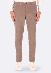 Pantaloni in velluto a coste marrone con righe verticali, dotati di chiusura frontale con bottone e zip, e tasche anteriori. Abbinati a sneaker bianche.