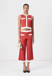 Rode gewatteerde crop top met witte accenten en hoge, wijde broekspijpen. Textuurstof met twee voorzakken en contrasterende zomen.