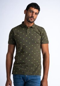 Polo shirt verde oliva in cotone, con piccoli motivi circolari verdi su tutto il tessuto. Maniche corte, colletto classico e orlo dritto.