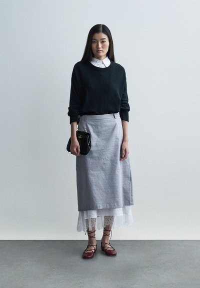 Czarny dziany sweter, szara lniana spódnica z koronkowym wykończeniem, czerwone baleriny na sznurowadła. Mała czarna skórzana torebka, gładkie faktury, casualowy warstwowy design.