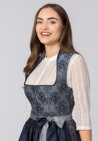 Traditionelles Dirndl mit einem marineblauen, floral gemusterten Mieder, weißer Spitzenbluse und einem satinierten grauen Band um die Taille. Ausgestellter Rockdesign.