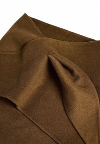 Pruun villakangas pehmea tekstuuriga, riietatud disainiga ja kihiliste voldidega, rõhutades selle soojust ja paksust.