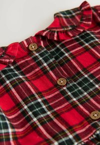 Camicia scozzese a quadri rossi e verdi con colletto arricciato, caratterizzata da bottoni in legno e una texture morbida, progettata con motivi a quadri.