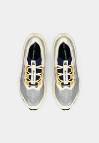 Zapatillas de running ligeras con parte superior de malla gris, media suela blanca y detalles en amarillo. Cuenta con cierre de cordones y suela texturizada.