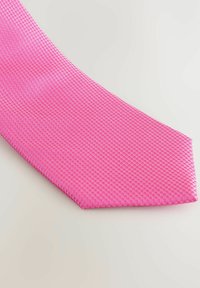 Jasnoróżowy krawat z teksturowanym wzorem w plaster miodu. Wąski koniec ostro się zwęża, ukazując gładkie wykończenie. Zaprojektowany do eleganckiego ubioru.