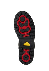 Sålen på en sort vinterstøvle med dybe slidbaner, røde isgrebsvedhæng, gult trekantet logo og præget mærkenavn "Bogner".